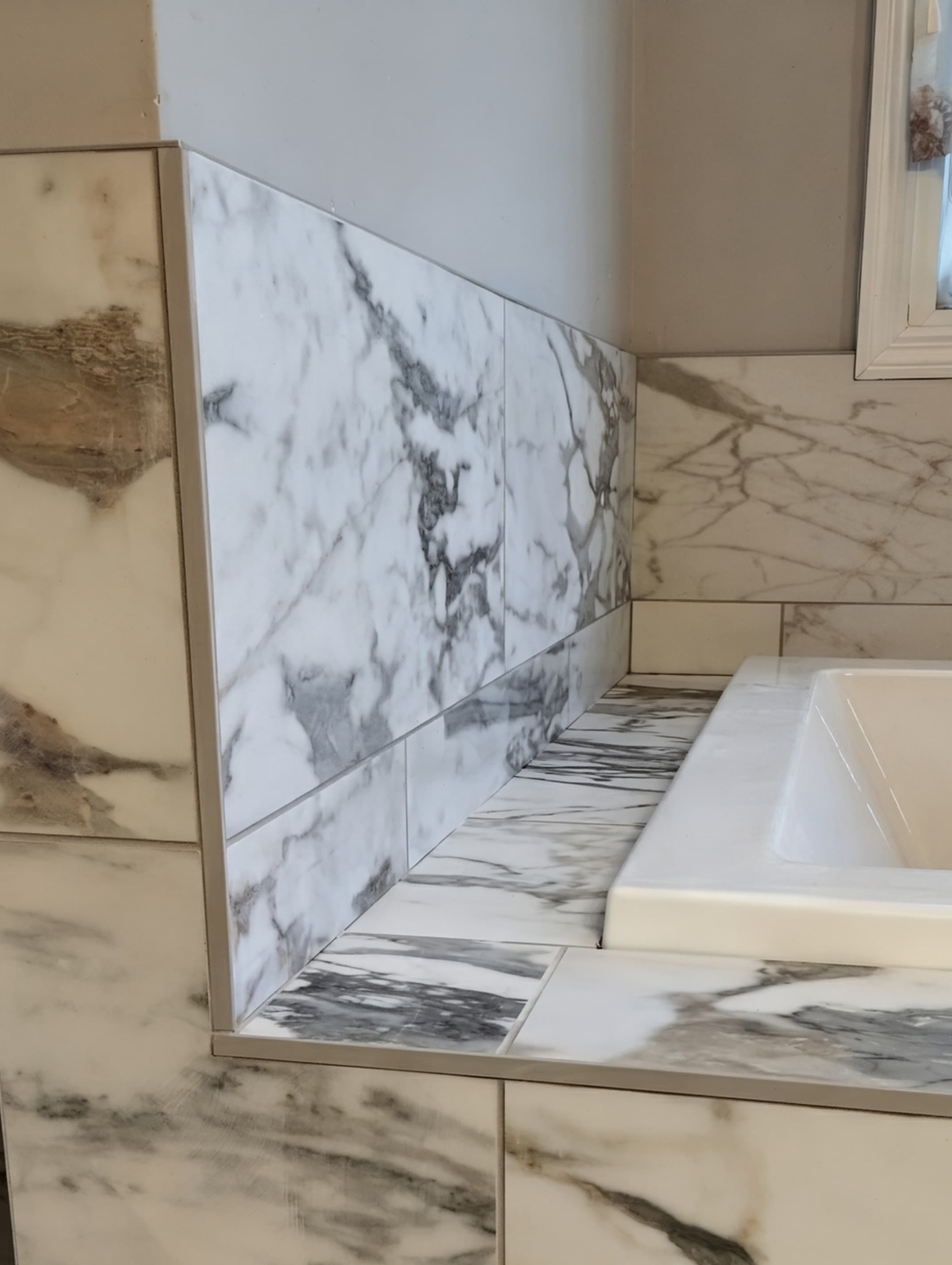 Marble tile surround around a drop-in tub installation.
